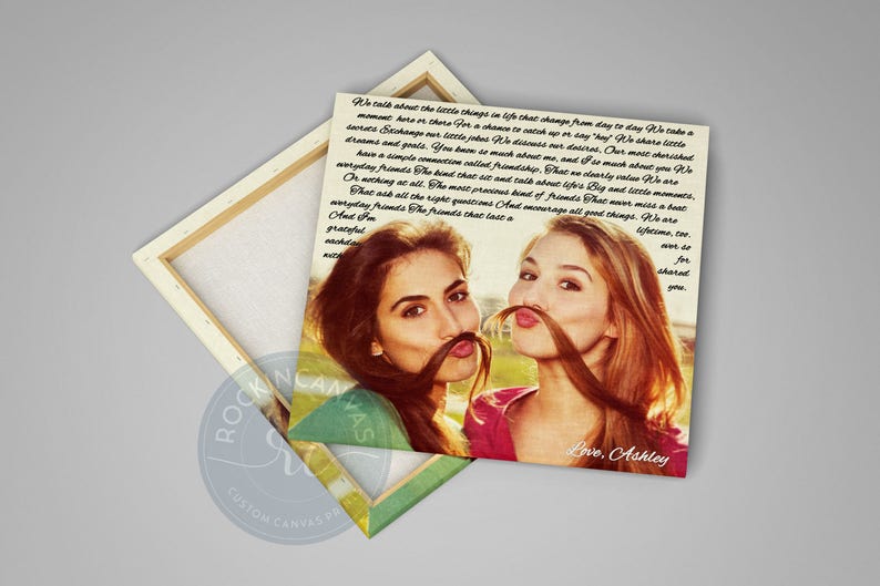 May include: A canvas print featuring two women posing with their hair styled as mustaches. The print has a light background with text and the words "Love, Ashley" at the bottom. The canvas is wrapped around a wooden frame.