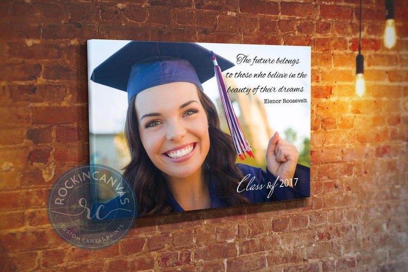 May include: A canvas print featuring a smiling graduate wearing a blue cap and gown. The print includes the quote "The future belongs to those who believe in the beauty of their dreams" and "Class of 2017". The Rockin Canvas logo is visible.