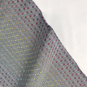 May include: Fabric with a repeating geometric pattern of black and white hexagons, each containing a smaller hexagon in a rainbow of colors. The fabric is folded, revealing a white background.