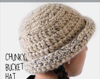 Könnte beinhalten: Ein grober Häkel-Fischerhut aus gesprenkeltem beigem und cremefarbenem Garn mit breiter Krempe. Der Text CROCHET PATTERN, CHUNKY BUCKET HAT und @MARVESnewyork ist auf dem Bild zu sehen und weist auf eine Anleitung für diese Kopfbedeckung hin.