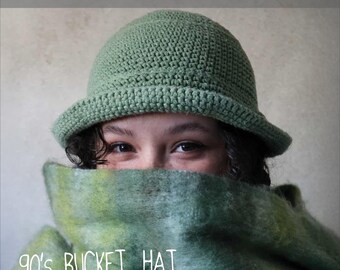 Könnte beinhalten: Ein salbeigrüner Häkel-Anglerhut mit abgerundeter Krone und kurzer, nach unten geneigter Krempe. Der Text CROCHET PATTERN und 90'S BUCKET HAT ist auf dem Bild zu sehen, zusammen mit dem Social-Media-Handle @MARVESNEWYORK.