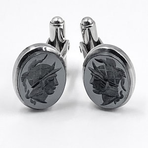 May include: A pair of silver cufflinks with a black cameo of a profile of a person wearing a helmet.