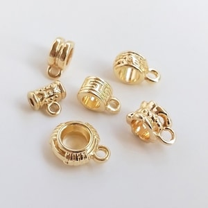 May include: Five gold-toned metal bead caps with different designs. The bead caps have a small loop at the top for attaching to a necklace or bracelet.