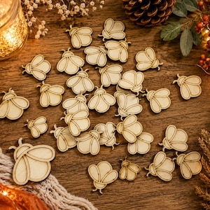 May include: A collection of small, light-colored wooden bee cutouts scattered across a surface. Each piece features a simple, engraved outline of a bee with rounded wings and a segmented body, showcasing a natural wood grain texture throughout.