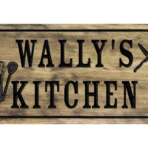 以下が含まれることがあります： 黒い文字で「WALLY'S KITCHEN」と書かれた木製の看板。看板は素朴な木目模様で、泡立て器、ヘラ、交差した2本のナイフで飾られています。
