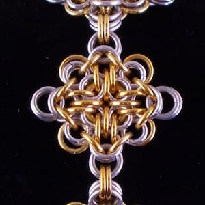 May include: A gold and silver bracelet with three square-shaped chainmail links. Each link is made of interlocking metal rings.