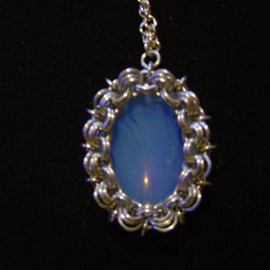 May include: A silver chain necklace with a pendant featuring a blue opal stone set in a silver wire frame.