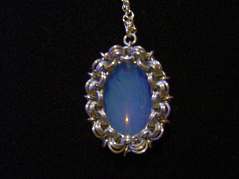 May include: A silver chain necklace with a pendant featuring a blue opal stone set in a silver wire frame.