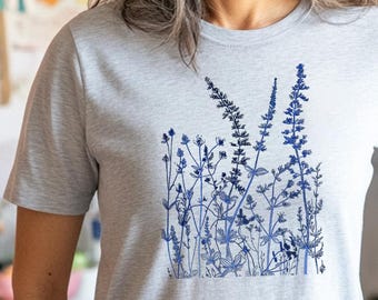 May include: A light gray t-shirt with a blue floral design. The design features a variety of flowers and leaves in a cluster.
