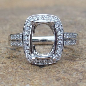 Anillo de oro blanco de 14 quilates con halo de diamantes. Montura semicircular de 7 x 10 mm.