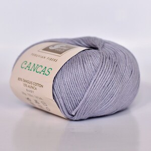 May include: A skein of light gray yarn labeled "Cancas" with the text "Peruvian Fibers 85% Tanguis Cotton 15% Alpaca Baby 50g 130m - 141 yds."