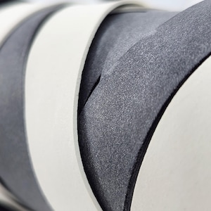 May include: Close-up of a white and gray fabric with a textured surface. The fabric is folded and layered, creating a pattern of overlapping curves.