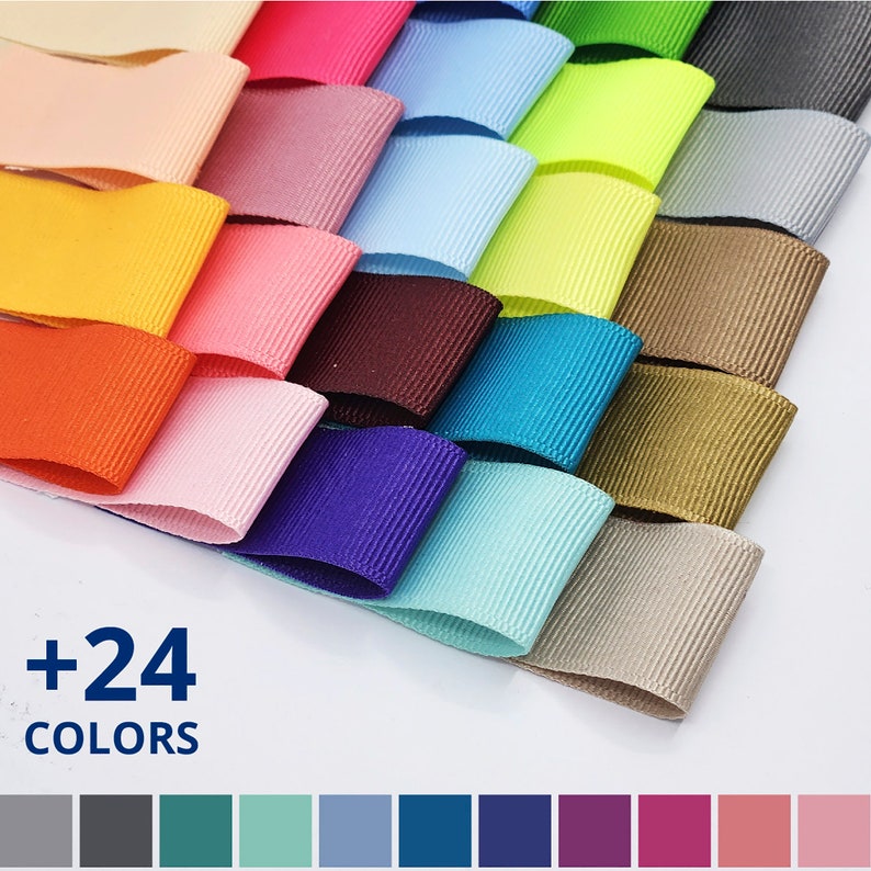 May include: A collection of 24 different colors of ribbon, arranged in a fan shape. The ribbon is a double-faced satin ribbon with a subtle ribbed texture. The colors include: beige, pink, yellow, orange, red, light pink, brown, teal, light blue, green, lime green, gray, gold, and more.