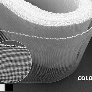 Può includere: Un rotolo di tessuto di tulle bianco con un bordo smerlato. Il primo piano mostra il dettaglio della maglia fine. L'immagine include il testo "3 COLORI" e una palette di colori grigio, bianco e nero.