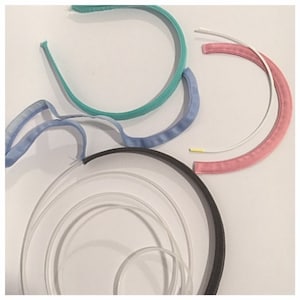 May include: Assortment of headbands in various colors and materials, including black, teal, pink, and blue. The headbands are made of fabric and plastic.
