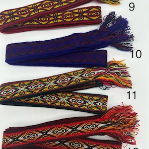 May include: Four woven fabric belts with fringe ends in various colors, including red, blue, yellow, and black. The belts are numbered 9, 10, 11, and 12.