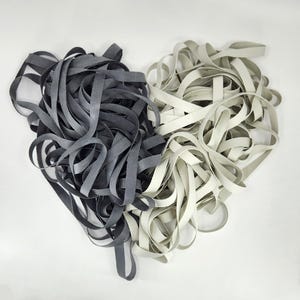 May include: A pile of black and white elastic bands. The bands are arranged in a heart shape.