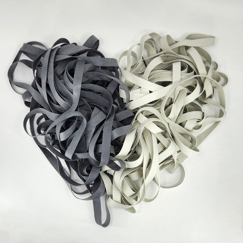 May include: A pile of black and white elastic bands. The bands are arranged in a heart shape.