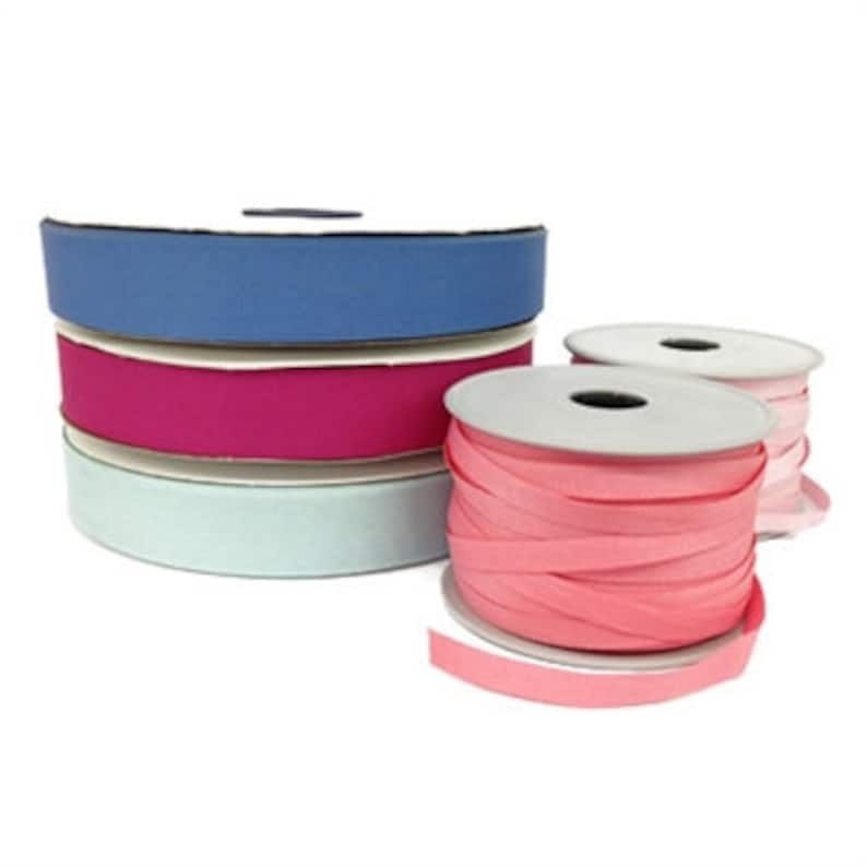 May include: Four spools of ribbon in various colors. The ribbon is a flat, woven fabric with a slightly textured surface. The colors are blue, pink, light blue, and peach.