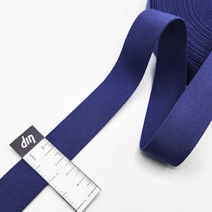 May include: A roll of dark blue elastic fabric with a ruler measuring 12.7 cm in length.