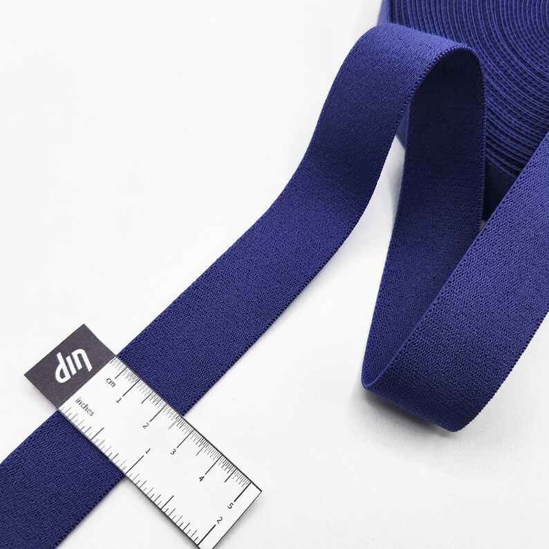 May include: A roll of dark blue elastic fabric with a ruler measuring 12.7 cm in length.
