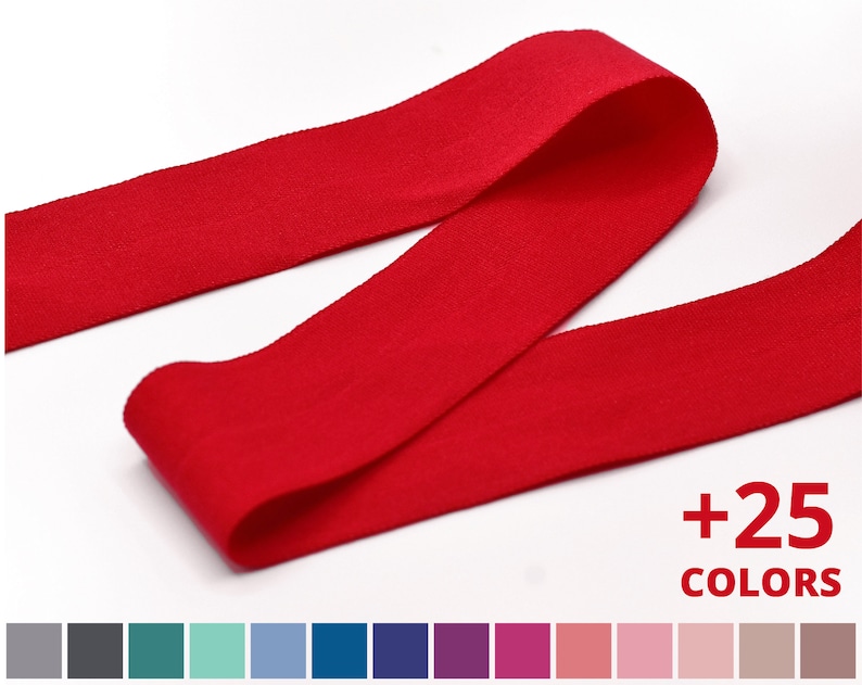 Peut inclure: Ruban en coton rouge avec une surface textur&eacute;e.  +25 COLORS est &eacute;crit en blanc sur fond noir.  Un nuancier pr&eacute;sente 25 couleurs diff&eacute;rentes de ruban.