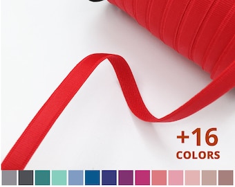 May include: A spool of red elastic ribbon with a close-up of the ribbon. The text +16 COLORS is visible below the ribbon.