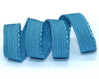May include: A close-up of a blue elastic trim with a scalloped edge. The trim is coiled and ready to be used for sewing or crafting projects.