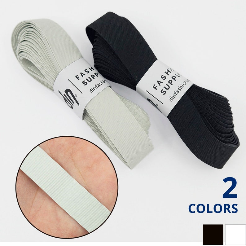 May include: Two rolls of elastic, one black and one light grey, with the text "FASH SUPPL dinfashion" on the labels. The text "2 COLORS" is below the rolls, with black and white squares representing the colours.