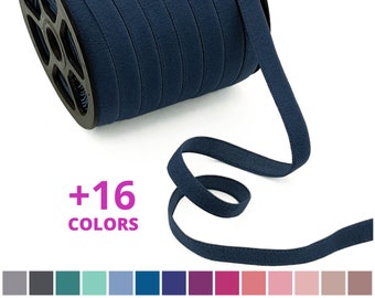 May include: A spool of navy blue elastic ribbon against a white background. The ribbon is 1.2 cm wide and is available in 16 colours. +16 COLORS