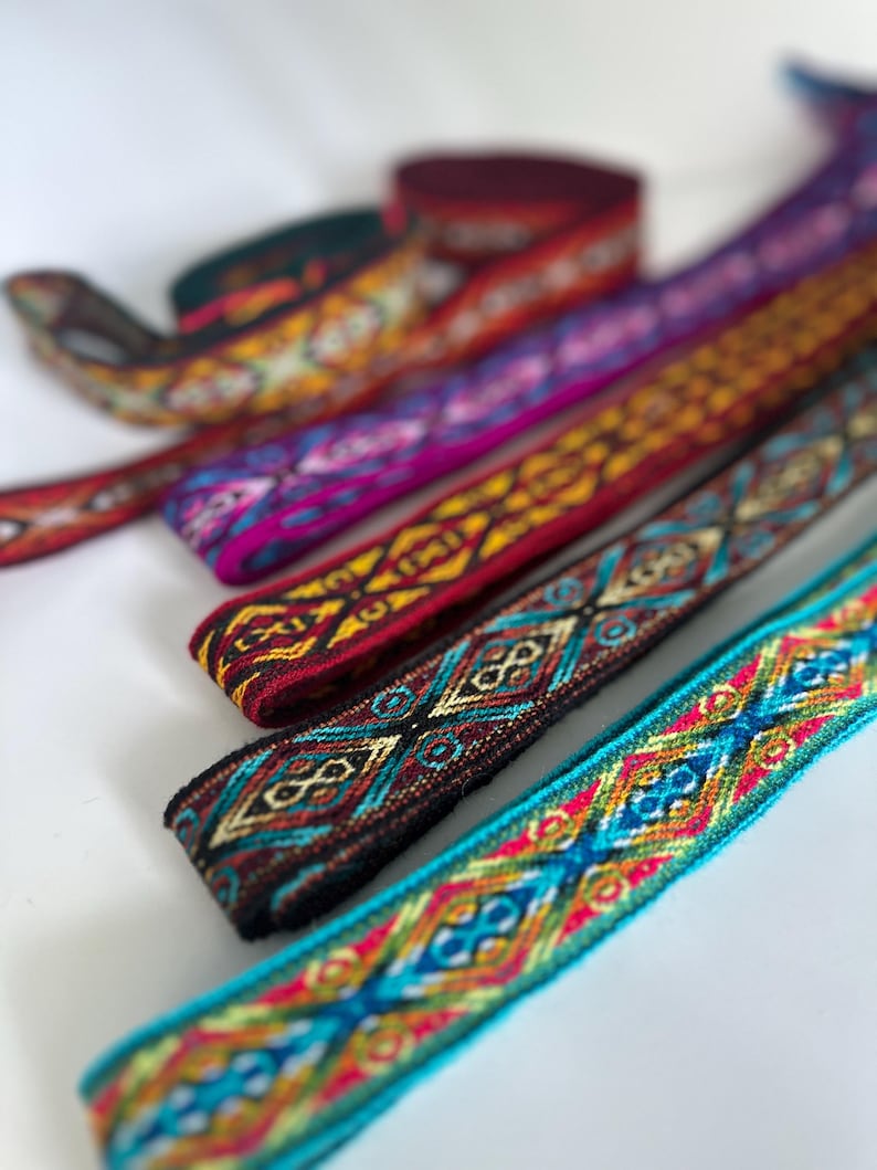 May include: Assortment of colorful woven ribbon trim with geometric patterns. The ribbon is made of a soft, textured fabric and features a variety of colors, including red, blue, yellow, green, and black.