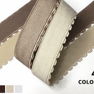 May include: Four colours of elastic trim with a scalloped edge. The trim is brown, beige, white, and black.