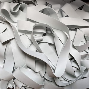 May include: A pile of white elastic bands, tangled and overlapping. The bands are smooth and appear to be made of rubber.
