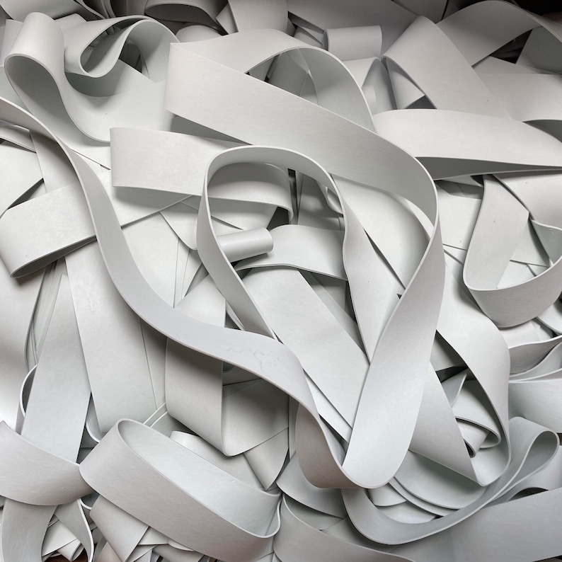 May include: A pile of white elastic bands, tangled and overlapping. The bands are smooth and appear to be made of rubber.