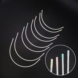 May include: A set of ten white metal bra strap adjusters with colorful plastic tips. The tips are in various shades of yellow, pink, blue, and green.