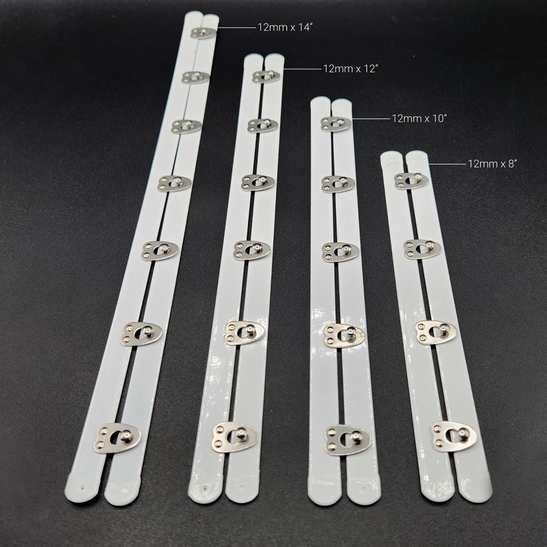 May include: Four white bra strap extenders with silver metal hooks and eyes. The extenders are 14 inches, 12 inches, 10 inches, and 8 inches long.
