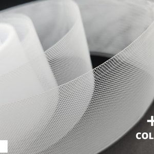 May include: White tulle ribbon with a fine mesh pattern. The ribbon is rolled up and shows the texture of the fabric. +2 Colors.