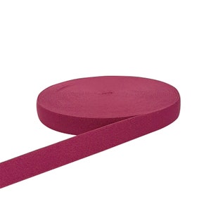 May include: A roll of burgundy elastic band, a type of fabric used for sewing and crafting.