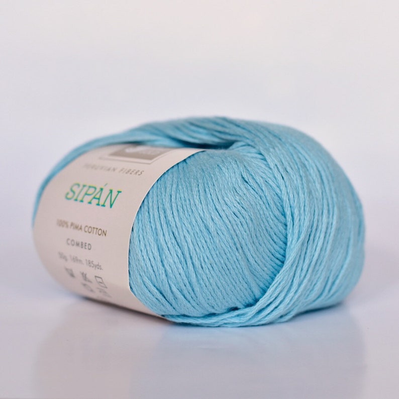 May include: A ball of light blue 100% Pima cotton yarn labeled "Sipan" with the words "Combed" and "100g 185yds" on the label.