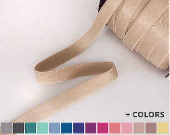 May include: A roll of beige elastic trim with a textured surface.  + COLORS is written below the roll.  A colour chart shows 14 different colours of elastic trim.