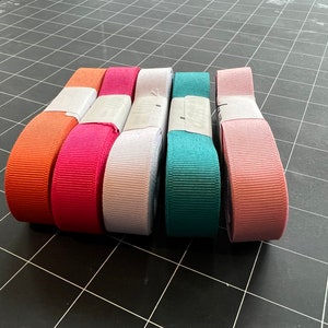 May include: Five spools of ribbon in various colors, including orange, pink, white, teal, and blush.