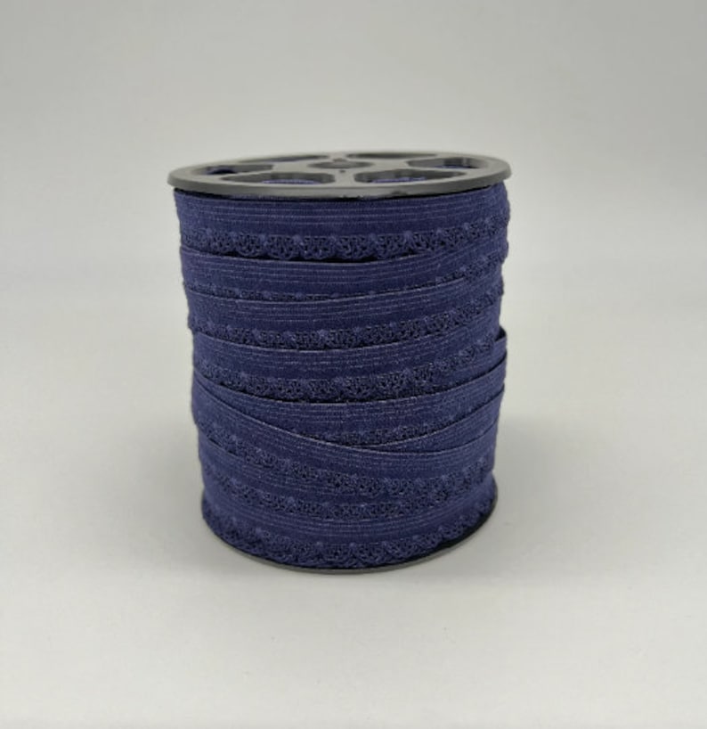 May include: A spool of navy blue elastic trim with a decorative scalloped edge.