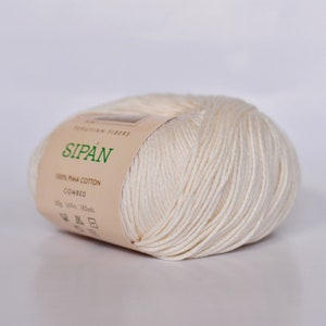 May include: A ball of off-white yarn labeled "SIPAN" with the text "100% PIMA COTTON COMBED 50g 160m 185yds" on the label.