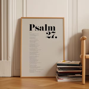 Pode incluir: Uma impressão emoldurada do Salmo 27 em texto preto sobre um fundo cinza claro. A moldura é de madeira clara e a impressão está pendurada em uma parede branca.