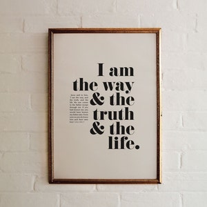 Peut inclure: Une impression encadrée avec un fond blanc et un texte noir qui dit "Je suis le chemin & la vérité & la vie." Le texte est en gras, police sans empattement. Le cadre est doré.