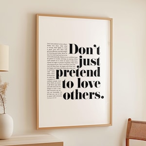 Puede incluir: Una impresión enmarcada en blanco y negro con el texto "Don't just pretend to love others." La impresión está sobre un fondo blanco y tiene un marco de madera.