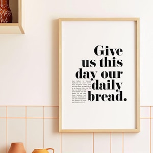 May include: A framed print with a black and white design. The text reads "Give us this day our daily bread."