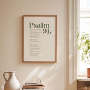 May include: A framed print with a beige background and a brown frame. The print features the text "Psalm 91." in a dark green font.