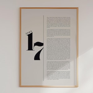 May include: A framed print with a black and white design featuring the name "John" and the numbers "17" in a bold, stylized font. The print includes a passage of text from the Bible, John 17:1-26.
