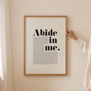 Puede incluir: Una impresión enmarcada en blanco y negro con el texto "Abide in me." La impresión presenta un versículo bíblico de Juan 15:4-17.